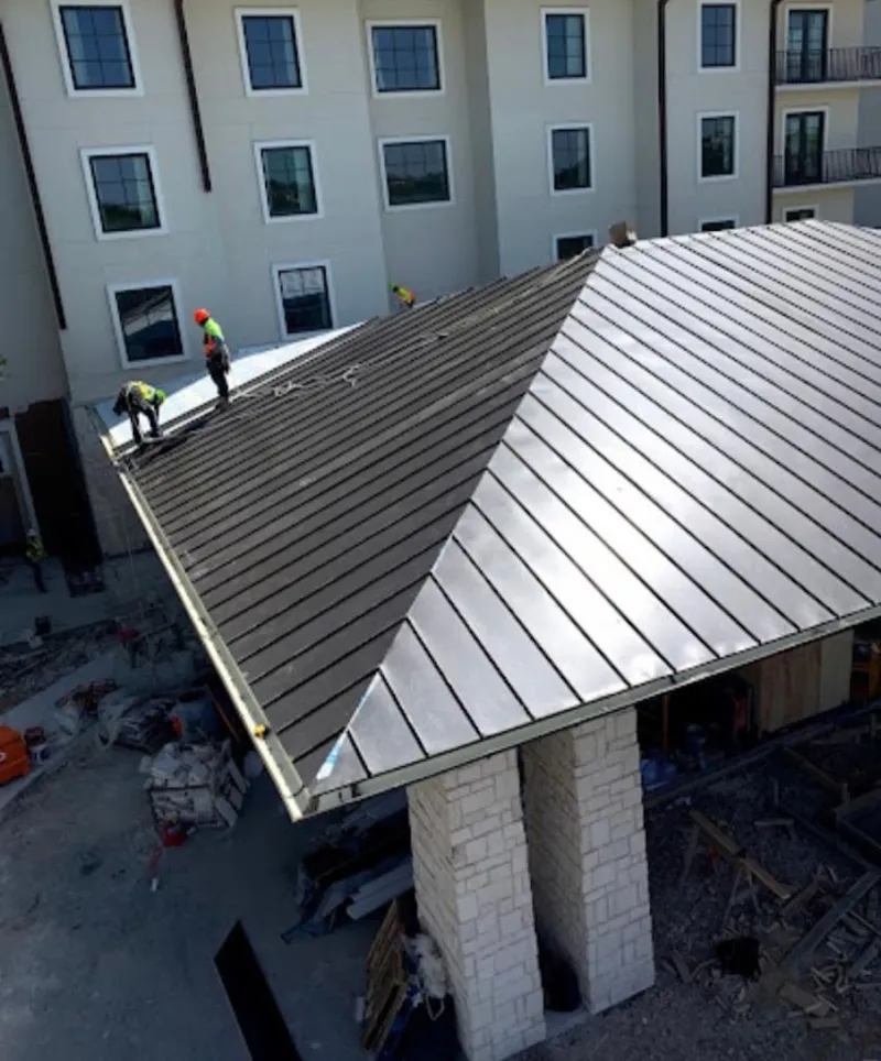 Crew installing standing seam metal roof panels on a commercial project in Placentia